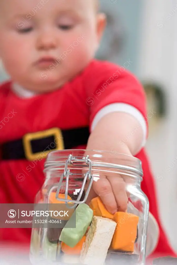 Baby taking sweets out of storage jar