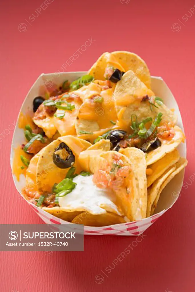 Tortilla chips with melted cheese in cardboard container