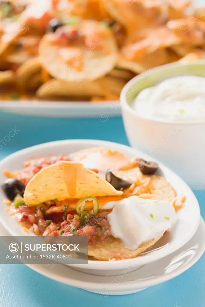Tortilla chips with melted cheese, olives and sour cream