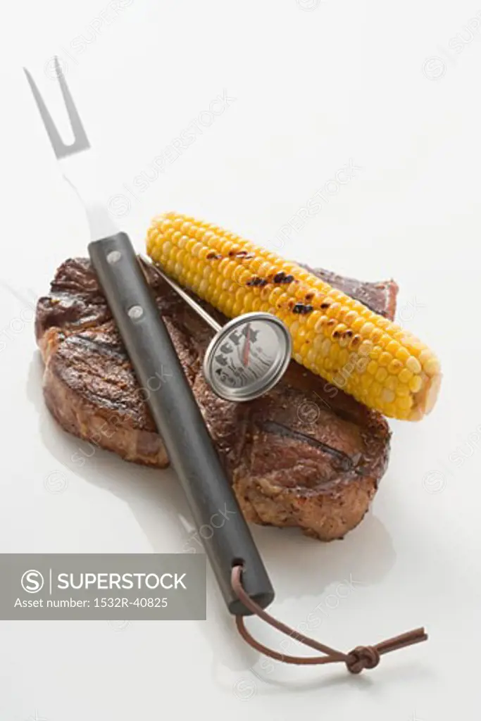 Beef steak with corn on the cob, carving fork & thermometer