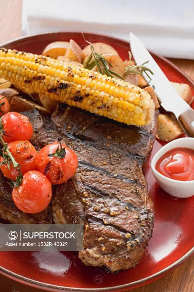 Grilled steak, corn on the cob, cherry tomatoes, potatoes, ketchup