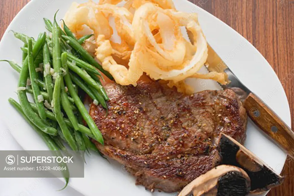Rib-eye steak with green beans and deep-fried onion rings