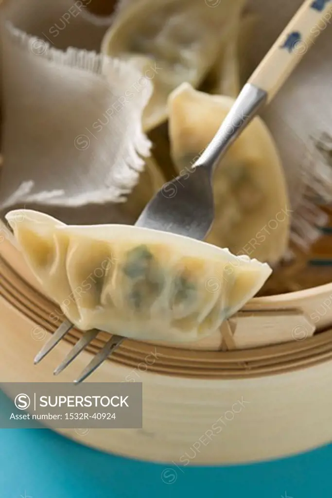 Wontons in bamboo steamer with fork (Asia)