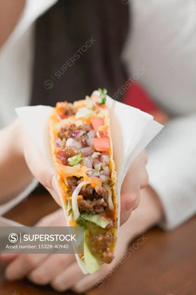 Woman holding mince taco in paper napkin