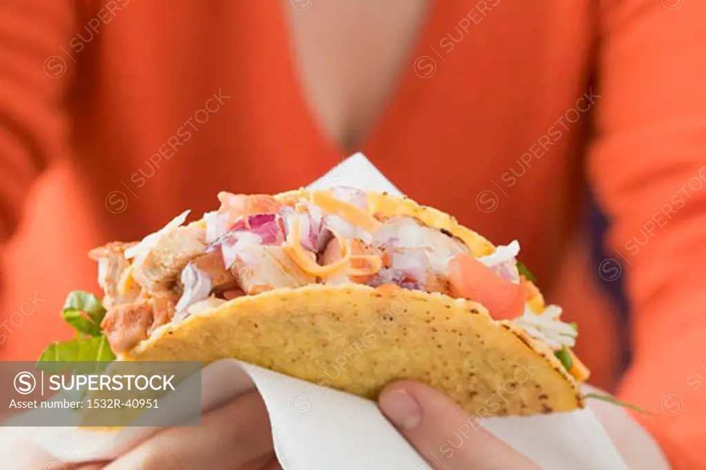 Woman holding chicken taco on paper napkin