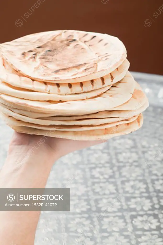 Hand holding stack of grilled flatbread
