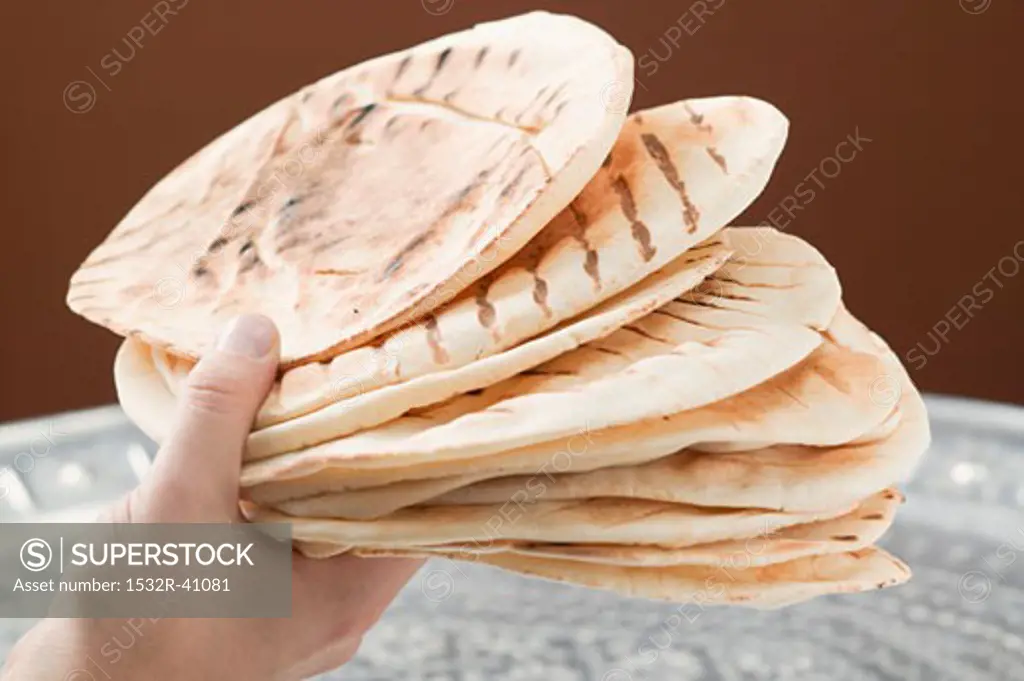 Hand holding several grilled flatbreads