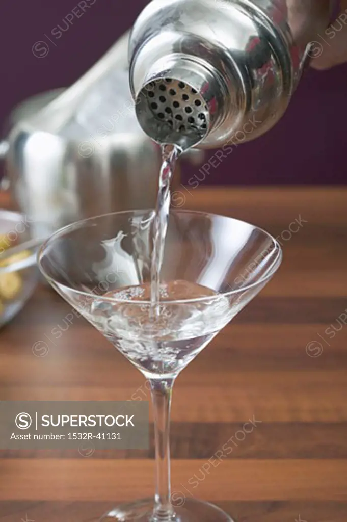 Pouring Martini out of cocktail shaker into glass