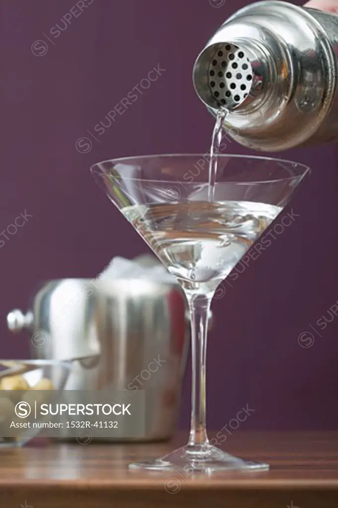 Pouring Martini out of cocktail shaker into glass