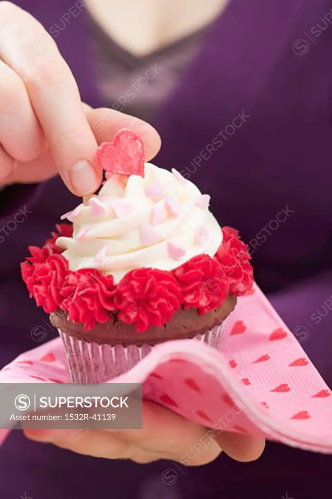 Woman holding Valentine's Day cupcake on paper napkin