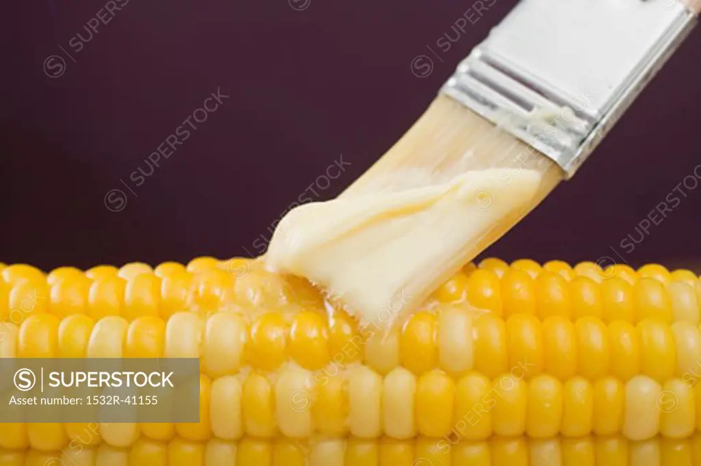 Brushing corn on the cob with butter