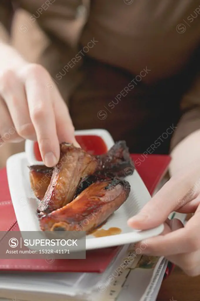 Woman eating glazed pork ribs in office