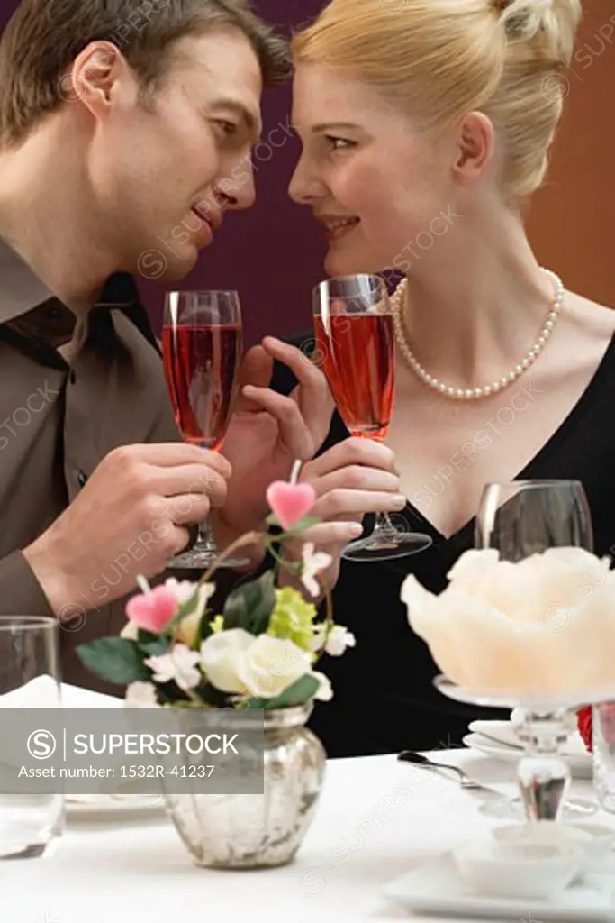 Couple with glasses of sparkling wine at laid table
