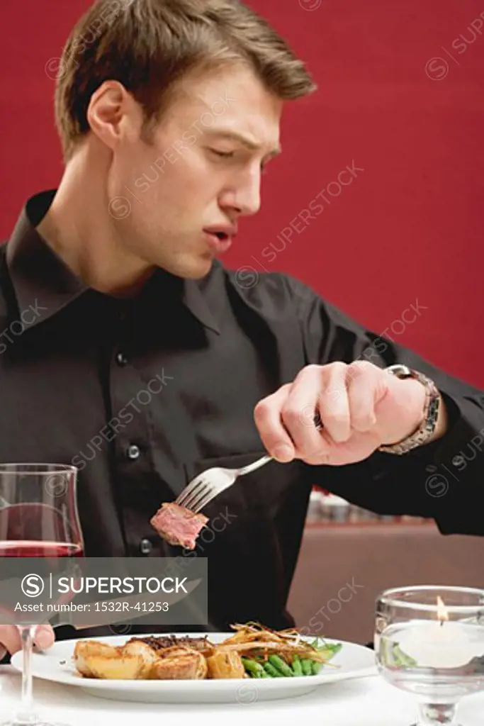 Impatient man eating steak in a restaurant