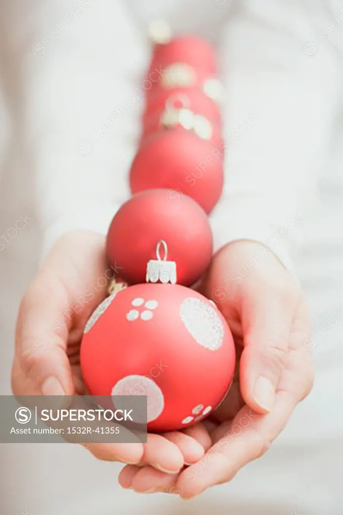 Hands holding red Christmas baubles