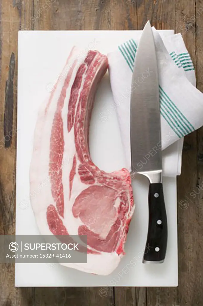 Fresh organic pork chop with knife on chopping board