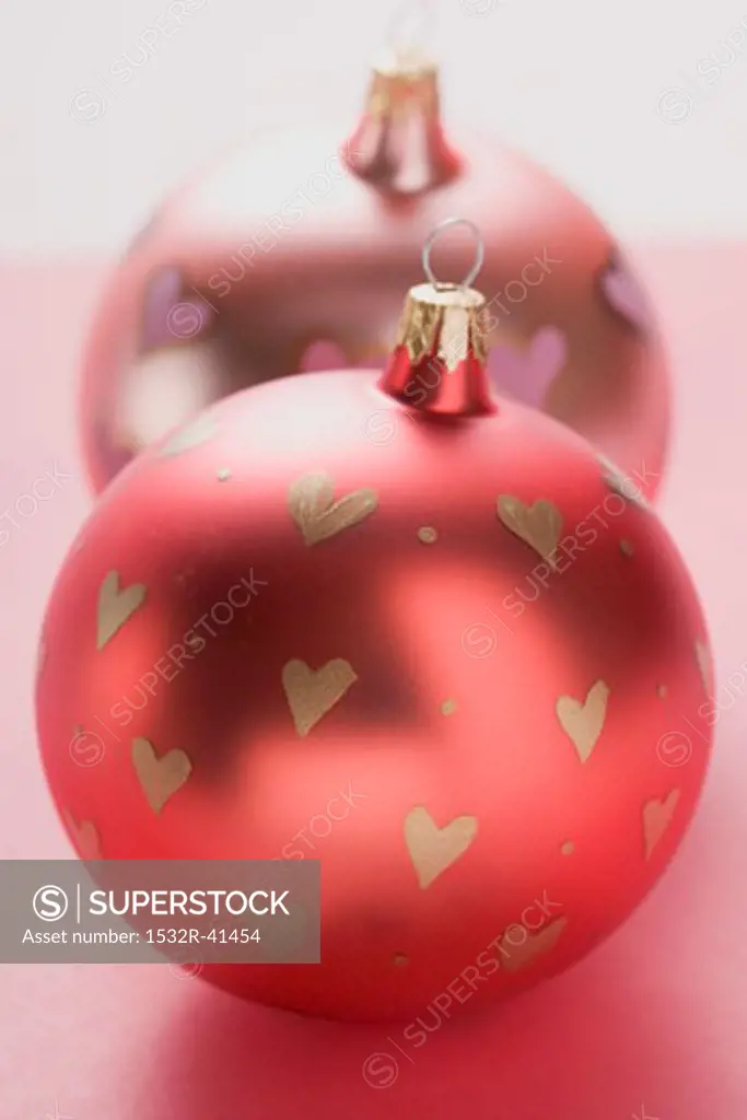 Two Christmas baubles with painted hearts