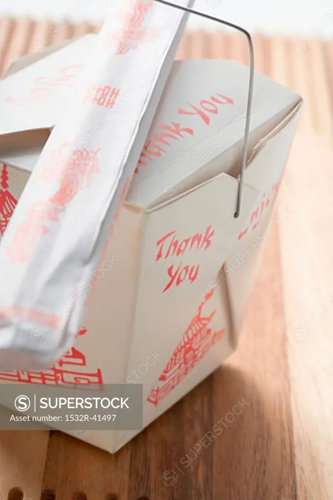 Asian snack in take-away box with chopsticks
