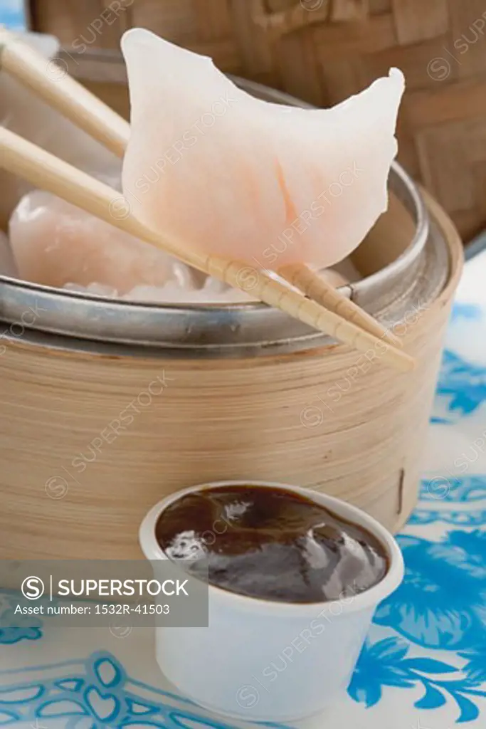 Dim sum in bamboo steamer and on chopsticks, dip (Asia)