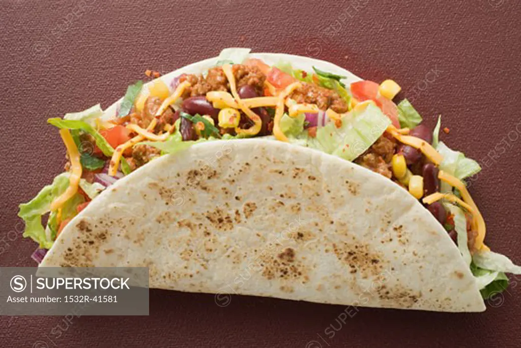 Taco filled with mince & cheese on brown background