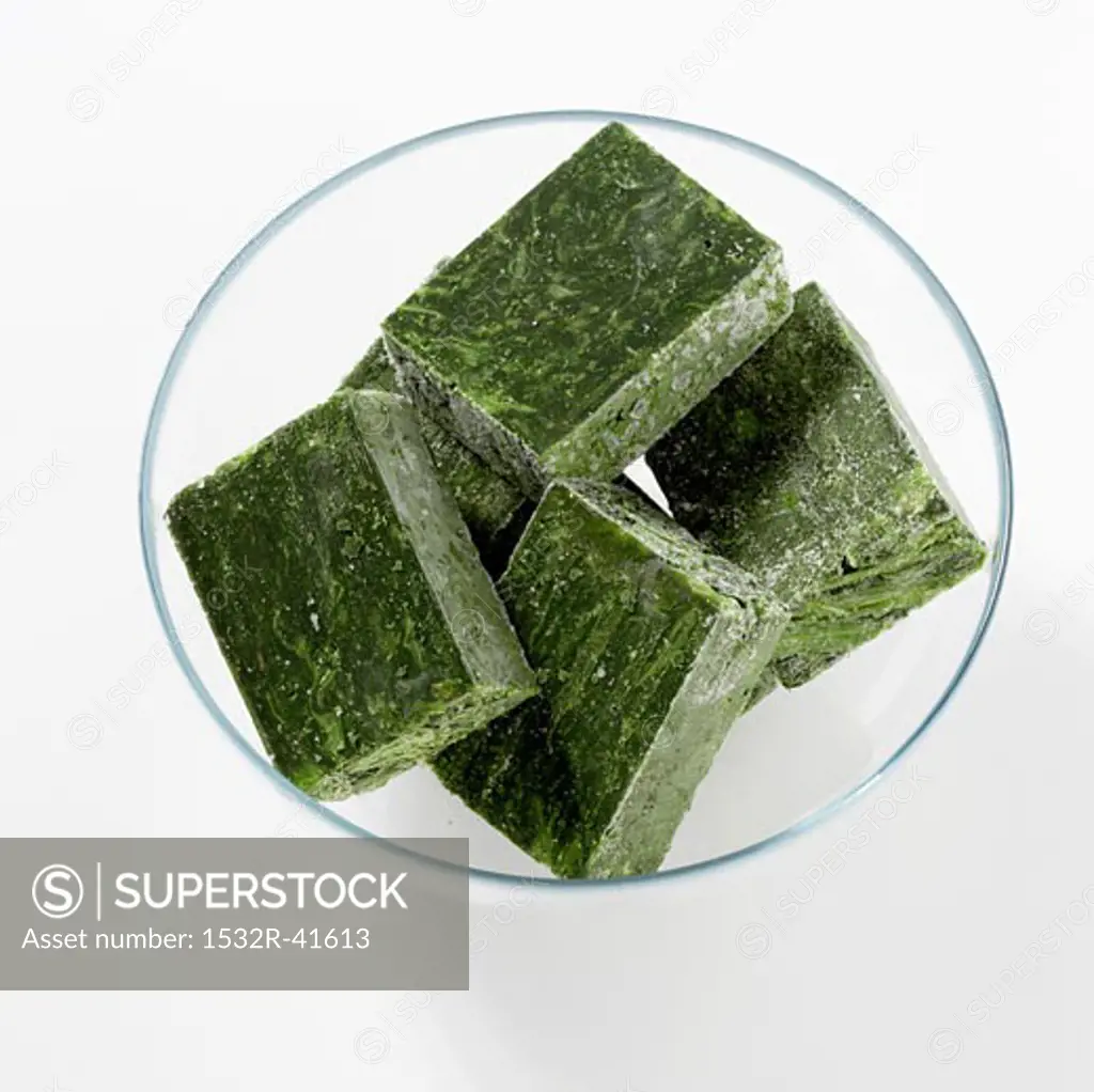 Cubes of frozen spinach in a glass bowl