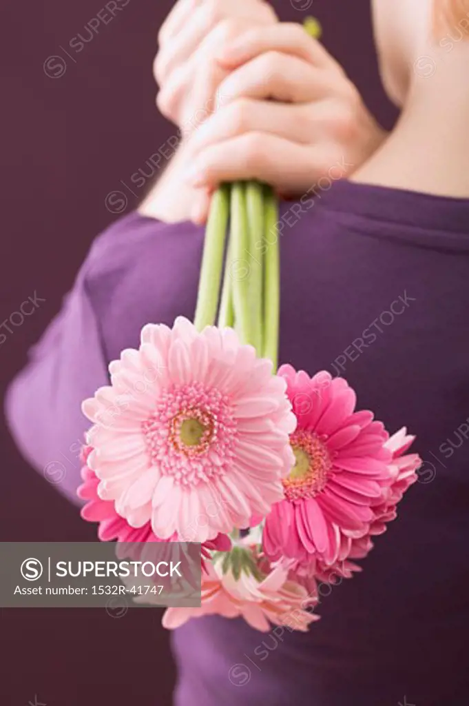 Woman holding bunch of flowers over her shoulder