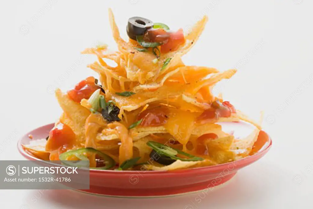 Nachos with cheese, olives, chilli rings & ketchup on plate