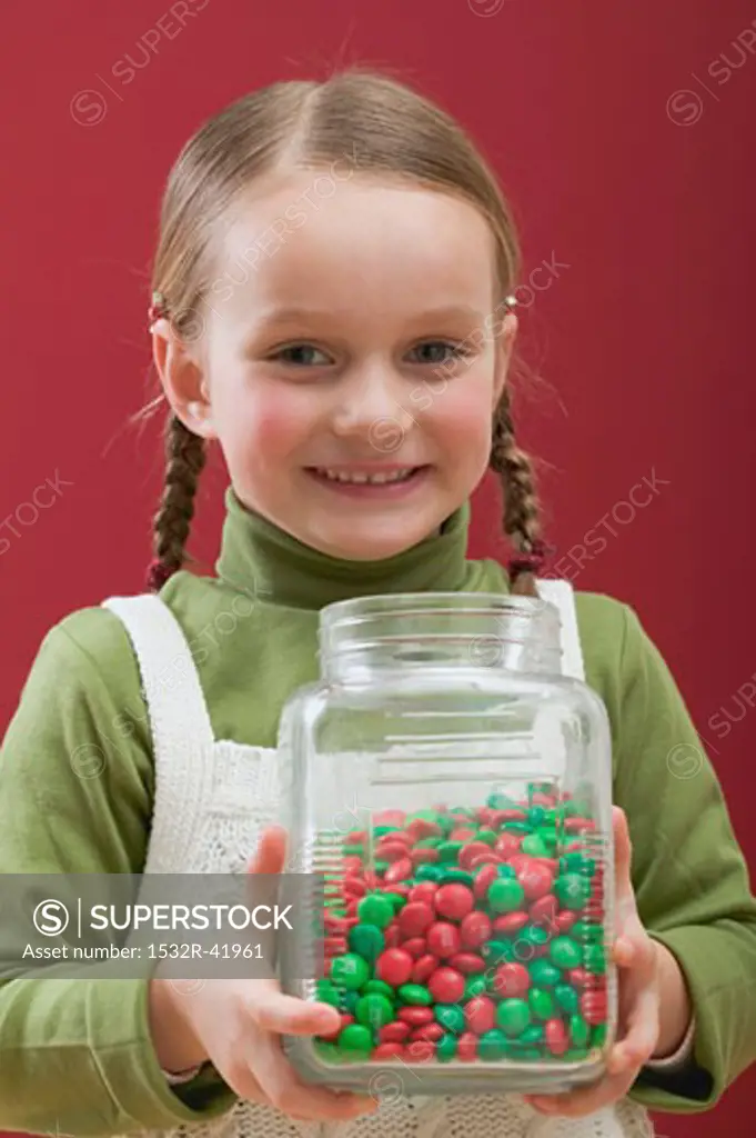 Small girl holding jar of chocolate beans