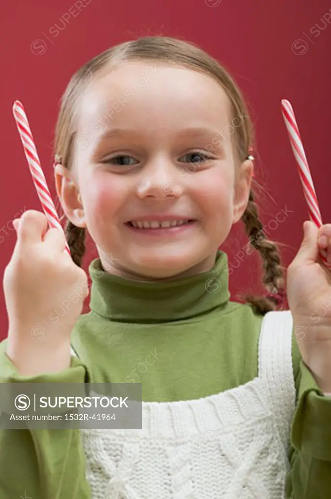 Small girl holding two candy canes