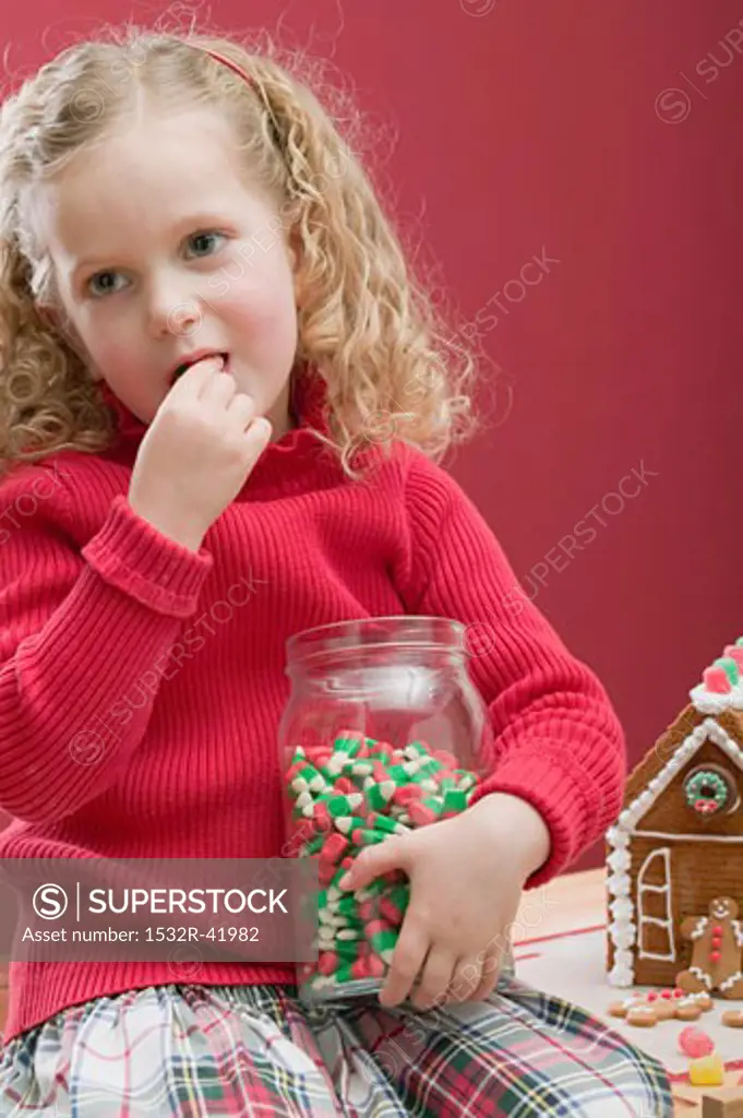 Small girl eating candy corn out of sweet jar