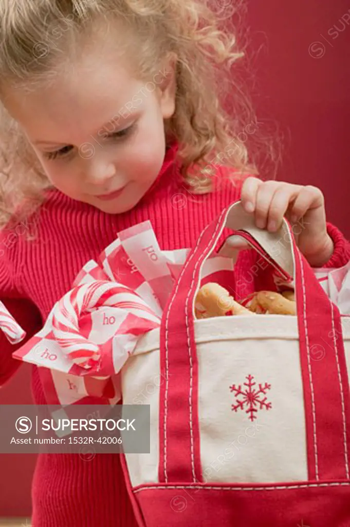Small girl holding bag of candy canes and biscuits