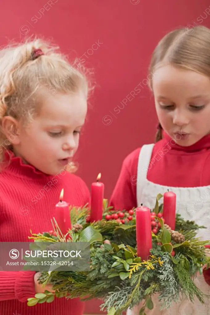 Two small girls blowing out candles on Advent wreath