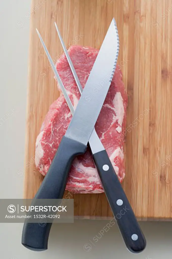 Beef steak on chopping board with meat knife and fork