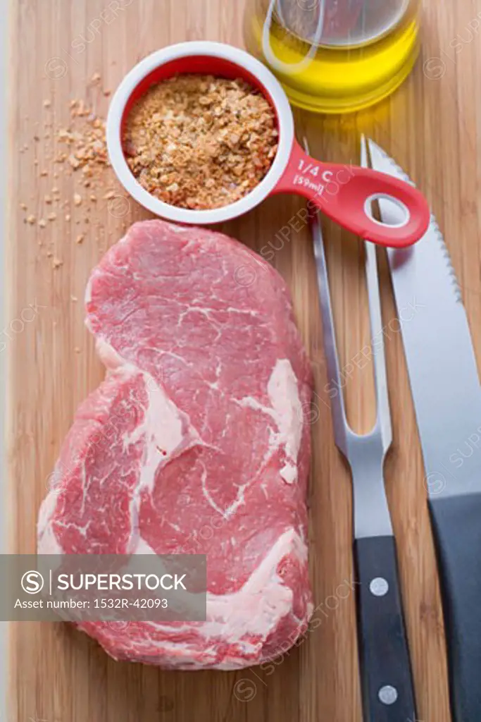Beef steak, spice mixture, cutlery and oil