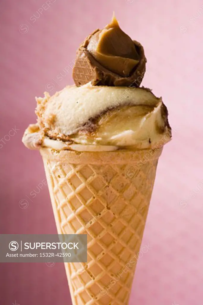 Caramel ice cream in wafer cone against pink background