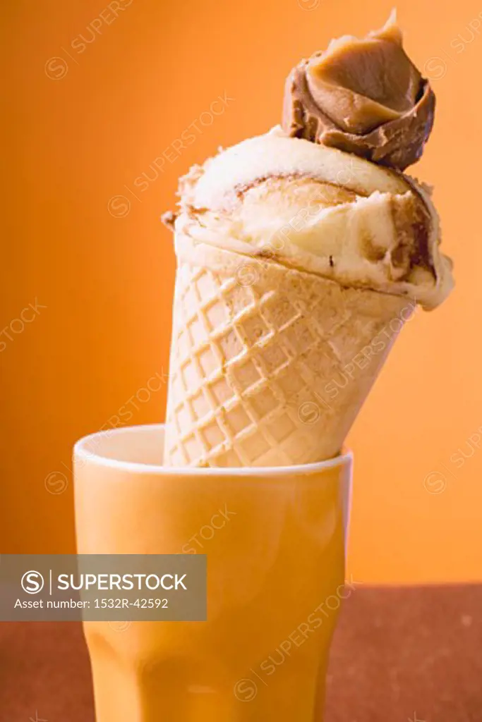 Caramel ice cream in wafer cone in orange beaker