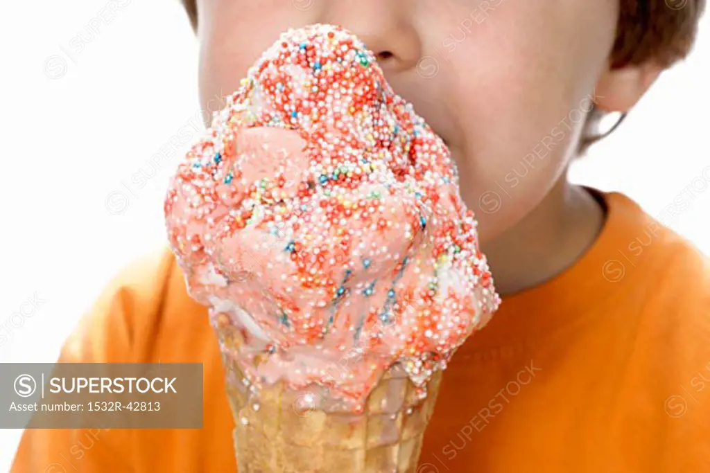 Boy holding large strawberry ice cream with coloured sprinkles