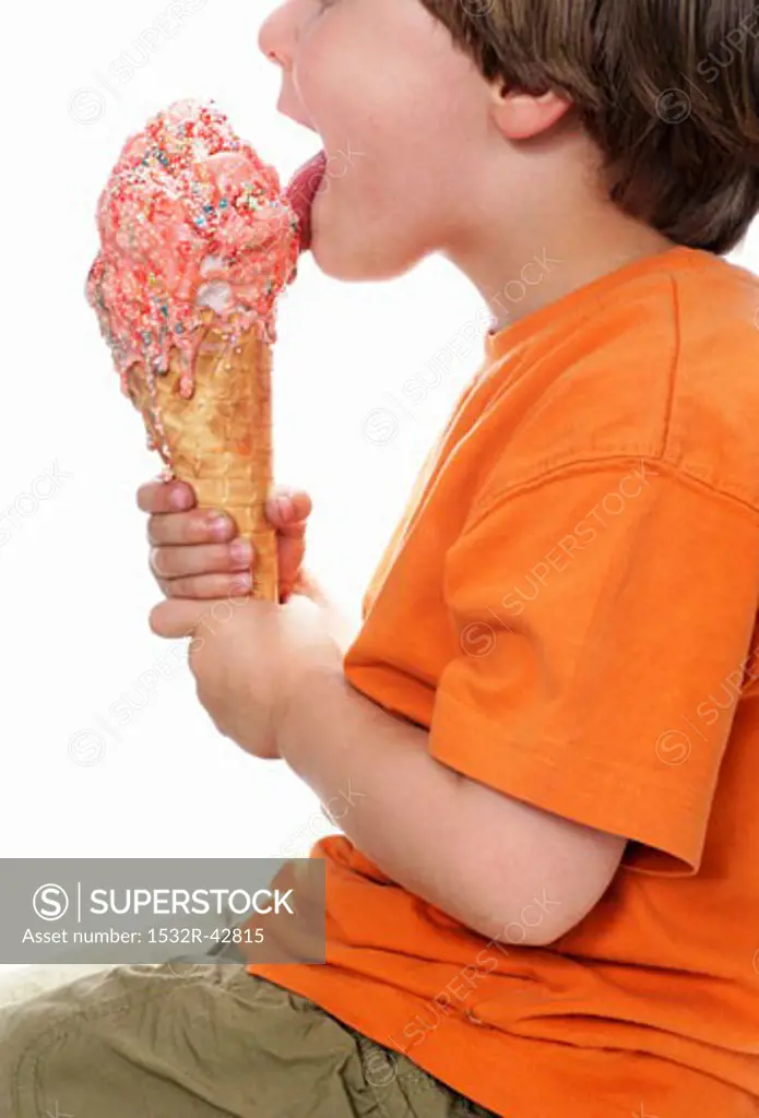 Boy licking a large strawberry ice cream with sprinkles