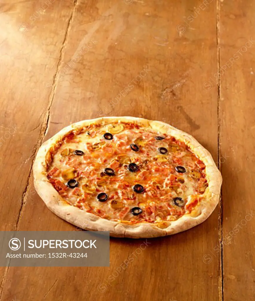 A pizza with mushrooms & black olives on wooden background