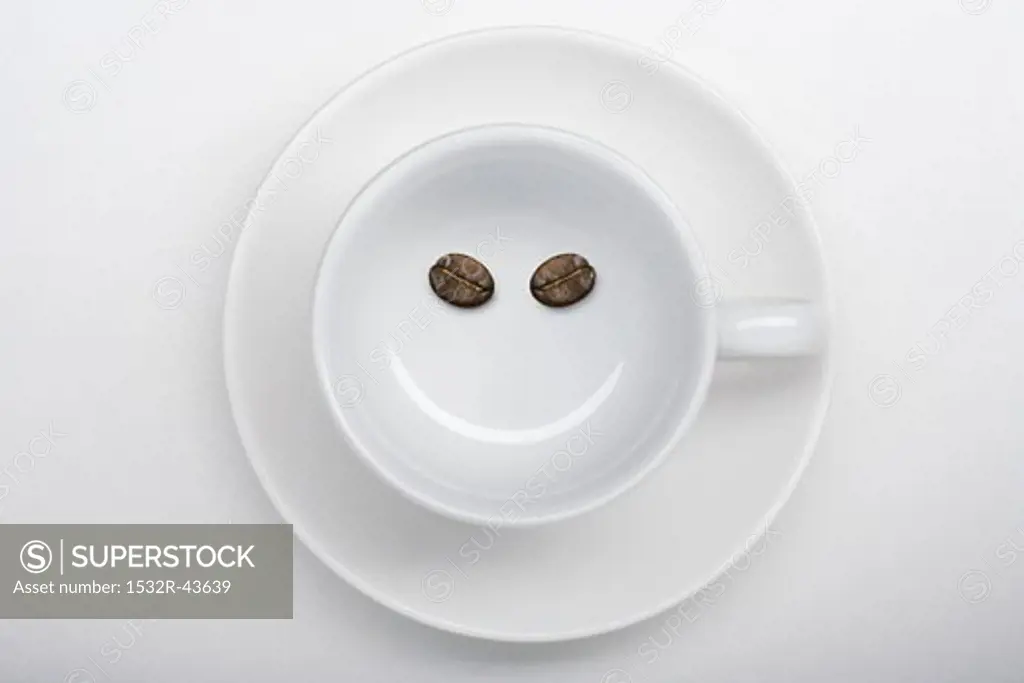 A coffee cup with two coffee beans making a smiley face