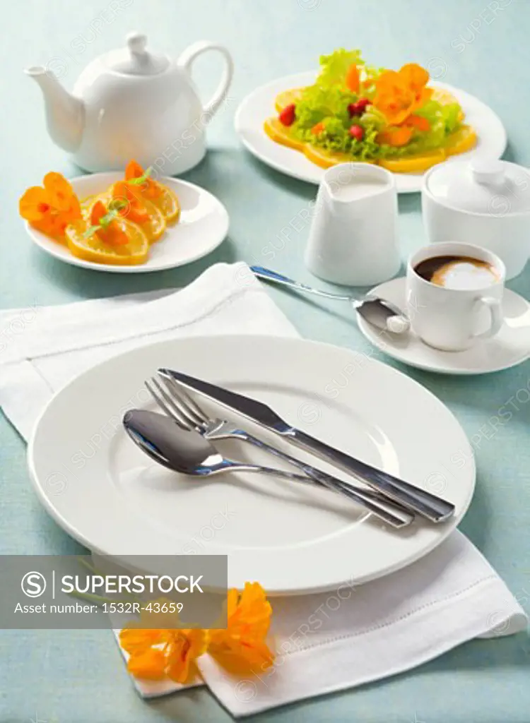 White place-setting with orange slices and coffee