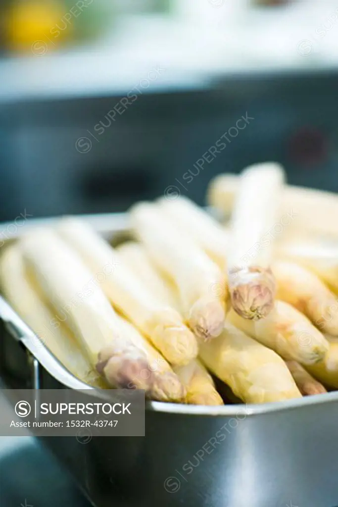 Peeled white asparagus spears in a roasting tin
