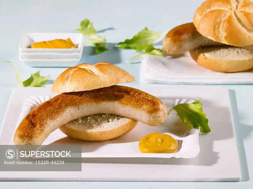 Two bread rolls filled with sausages on paper plates