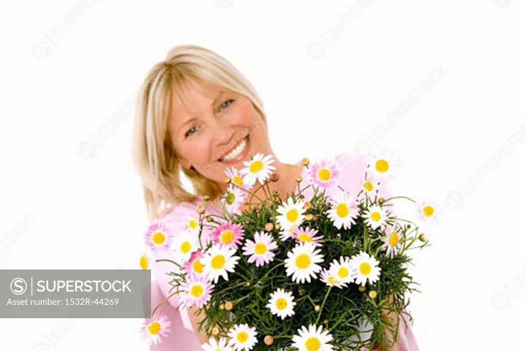 Cheerful woman holding bouquet of marguerites in her hands