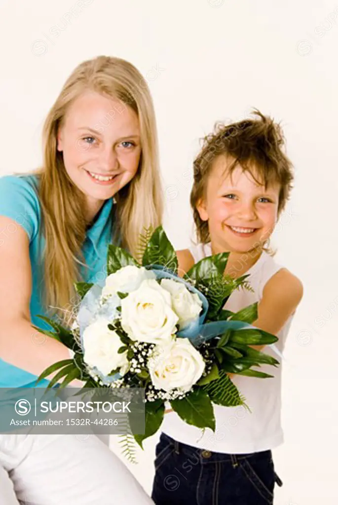 Two children holding bouquet of white roses in their hands