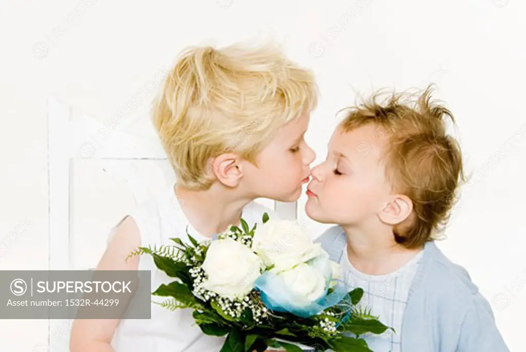 Two children kissing over a bouquet of white roses