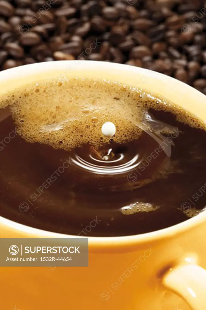A drop of milk falling into a cup of coffee