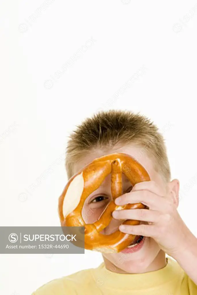 Boy holding a pretzel in front of his face