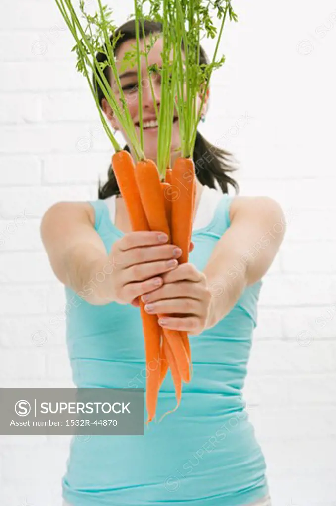 Woman holding out fresh carrots