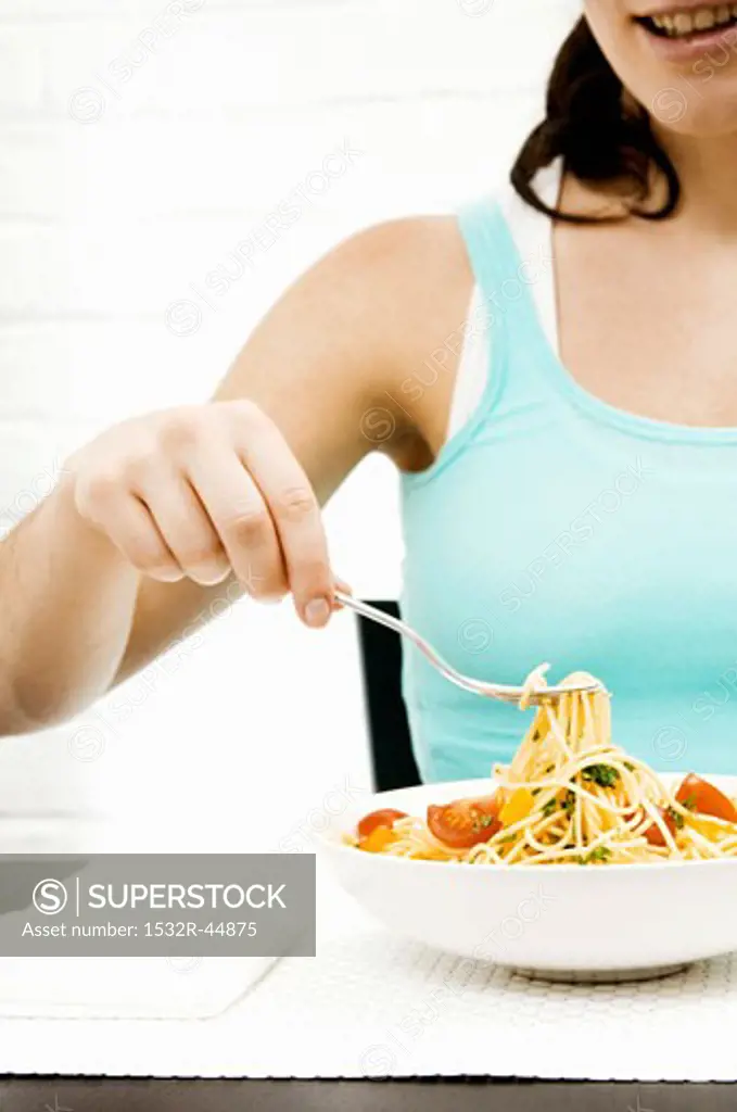 Eating spaghetti with herbs and vegetables